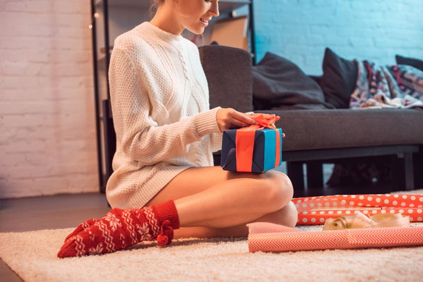 cropped view of woman sitting and wrapping present at christmas time  - Photo, Image