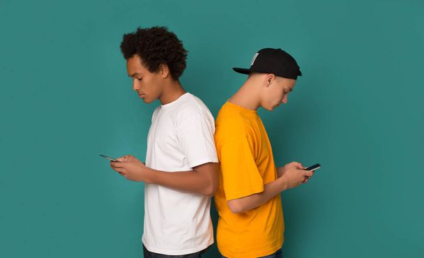 Smartphone addiction. Friends standing back to each other - Φωτογραφία, εικόνα