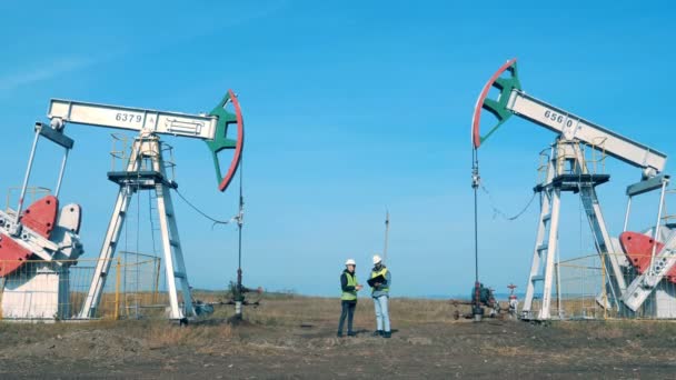 Erdölförderstätte mit zwei Ingenieuren, die untereinander kommunizieren. Energie, Öl, Gas, Treibstoffpumpe. - Filmmaterial, Video