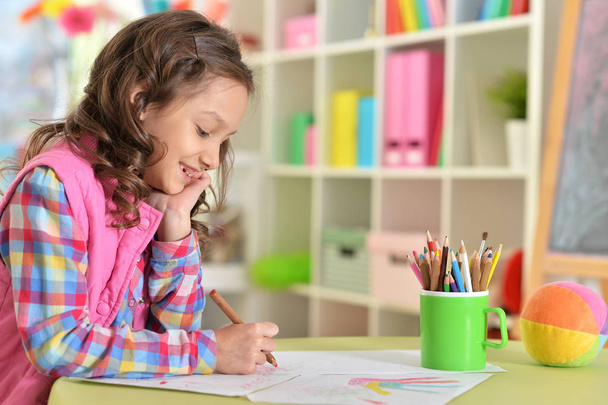schattig klein meisje tekening zittend aan tafel thuis - Foto, afbeelding