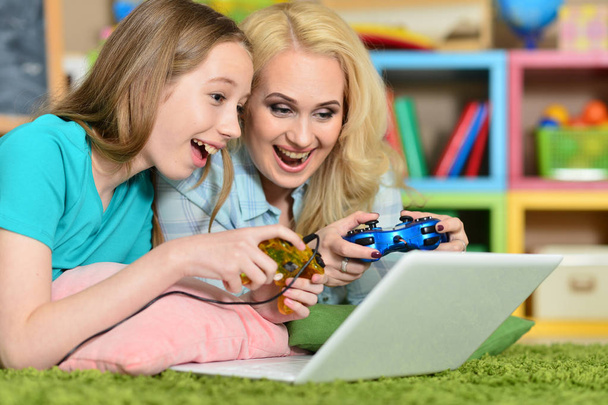 Young woman with  girl using laptop at home on floor playing - Photo, Image