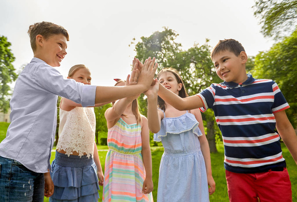 група щасливих дітей, які роблять високі п'ять на відкритому повітрі
 - Фото, зображення