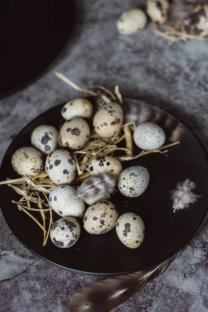 Raw quail eggs on black plate, easter concept, dark concrete background, top view - Fotoğraf, Görsel
