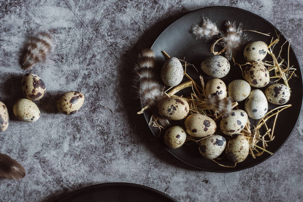 Raw quail eggs on black plate, easter concept, dark concrete background, top view - Foto, Imagen