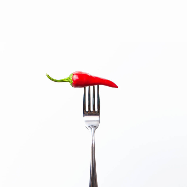Pimienta roja amarga en el tenedor sobre fondo blanco aislado. Concepto de alimentos creativos
 - Foto, Imagen