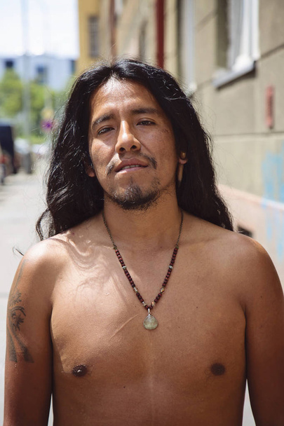 City portrait of young latino man with long hair and jewelry - Photo, Image