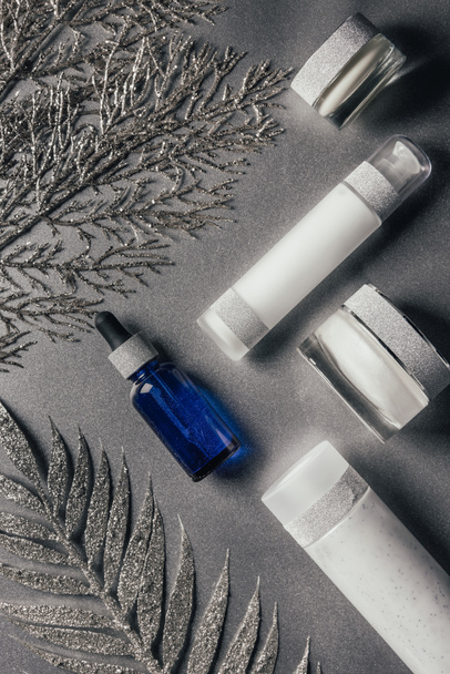 view from above of beauty cream, serum and lotion with decorated branches on silver - Fotografie, Obrázek