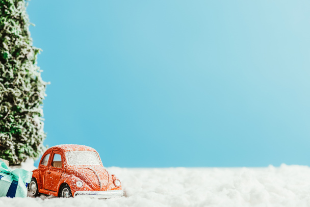 ギフトやクリスマス ツリーを踏んで雪青の背景に綿製のおもちゃの車のクローズ アップ ショット - 写真・画像
