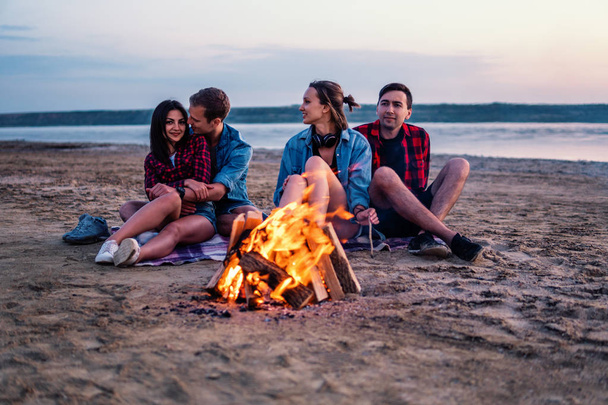 Młodzi przyjaciele urządzić sobie piknik z ogniskiem na plaży - Zdjęcie, obraz