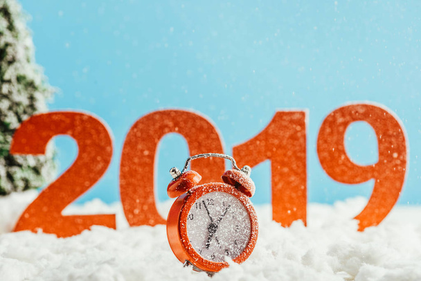 big red 2019 numbers with alarm clock standing on snow on blue background, new year concept - Photo, Image