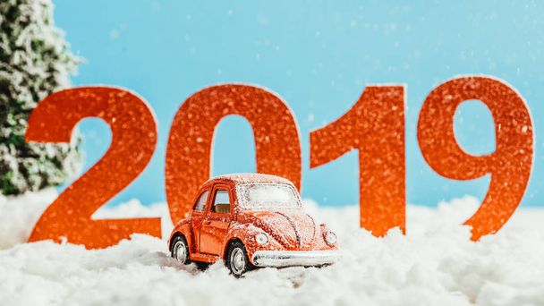 big red 2019 numbers with toy car standing on snow on blue background, new year concept - Foto, Imagen