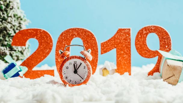 big red 2019 numbers with vintage alarm clock and gifts on snow on blue background, new year concept - Photo, Image