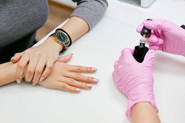 Master of manicure puts a nail polish on the girl's nails - 写真・画像