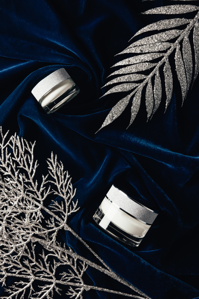 top view of beauty cream between silver decorated branches on velvet surface  - Photo, Image