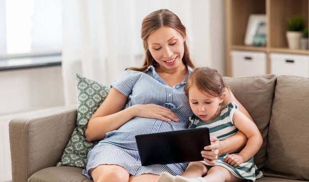Schwangere Mutter und Tochter mit Tablet-PC - Foto, Bild