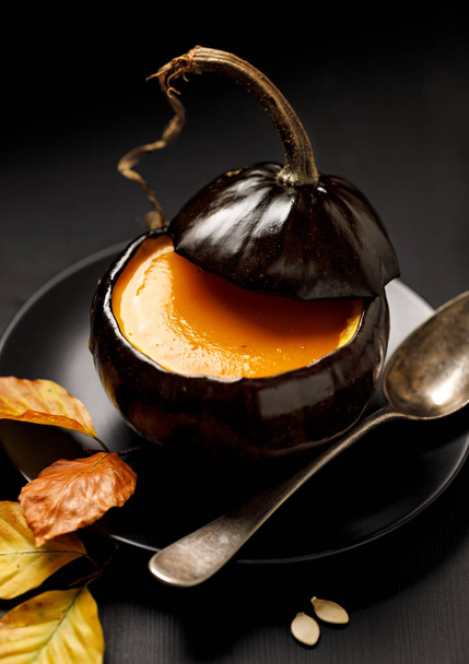 Pumpkin  soup served in a baked hollow pumpkin on a black background, delicious and beautiful. - Photo, Image