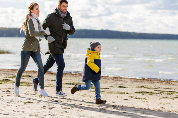 happy family running along autumn beach - Fotoğraf, Görsel