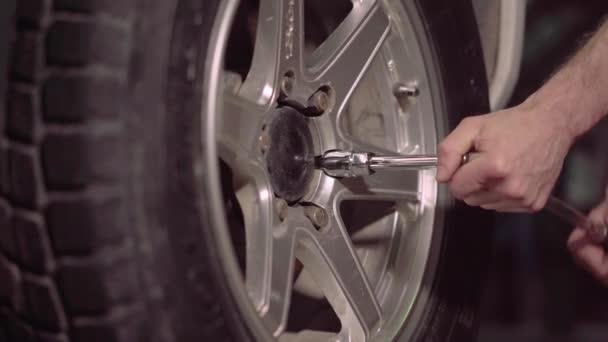 Automechanik v poli garáže zpřísňuje kontroly pomocí klíč šok utáhnout auto pneumatiky nut.4k,30fps. - Záběry, video