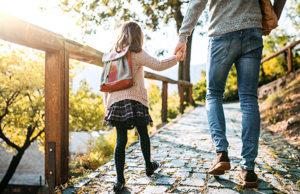 Dikiz bir genç baba kasabada küçük kızı ile sonbaharda yürüyüş. - Fotoğraf, Görsel