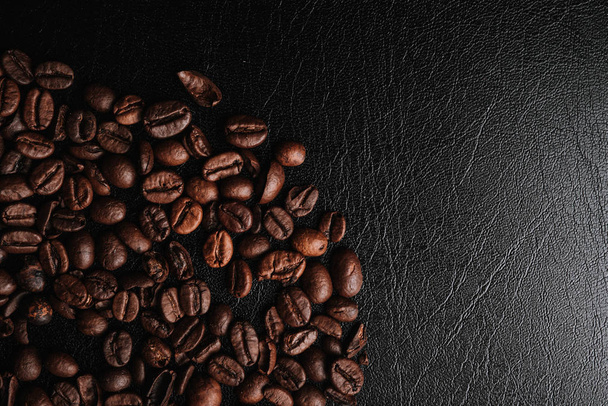 partial view of brown coffee beans, coffee background on black leather surface - Fotografie, Obrázek