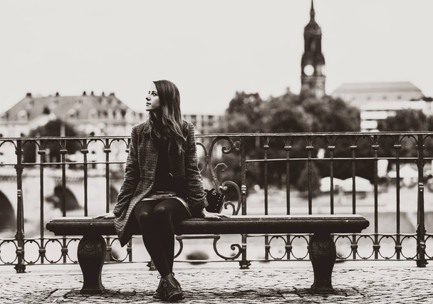 Tyttö istuu penkillä lähellä jokea Dresdenissä
. - Valokuva, kuva