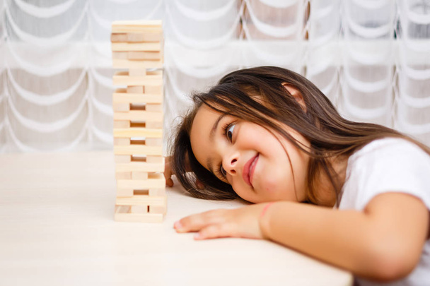 Mała brunetka dziewczyna gra z drewnianymi klocków w domu  - Zdjęcie, obraz