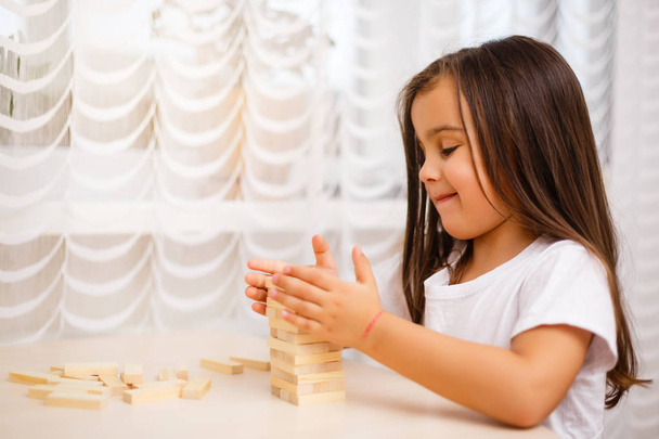 Little brunette girl playing with wooden blocks at home  - Φωτογραφία, εικόνα