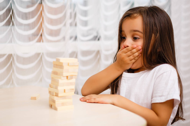 Little brunette girl playing with wooden blocks at home  - Foto, imagen