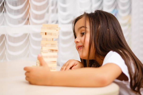Little brunette girl playing with wooden blocks at home  - Fotografie, Obrázek
