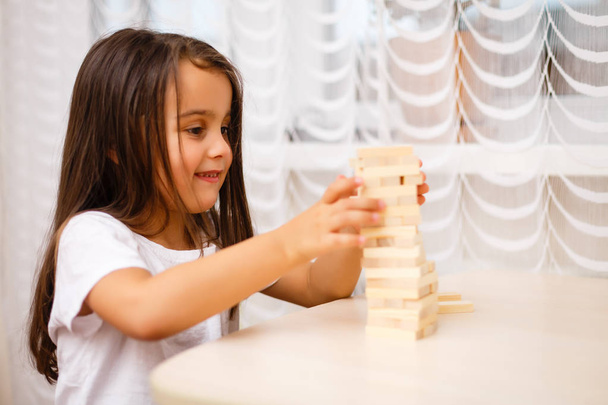 Little brunette girl playing with wooden blocks at home  - Foto, Imagem