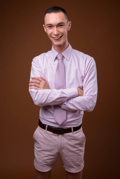 Молодой красивый андрогинный бизнесмен на коричневом фоне
 - Фото, изображение