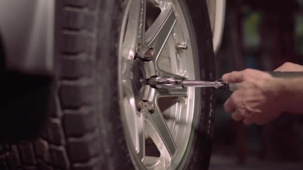 A garázs mezőben autószerelő szigorítja ellenőrzések segítségével egy sokk csavarkulcs, húzza az autó gumiabroncs nut.4k,30fps. - Felvétel, videó