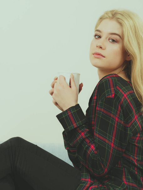 Young adult or teenage woman enjoying her leisure time drinking coffee or tea from mug. - Foto, Imagen
