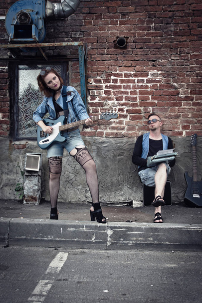 Το κορίτσι και ο τύπος πανκ σε δρόμο της πόλης παίζουν στις κιθάρες - Φωτογραφία, εικόνα
