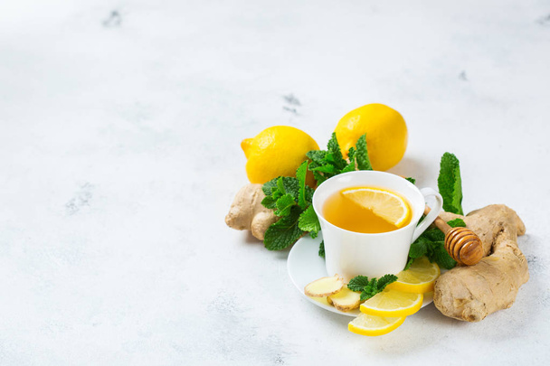 Food and drink, still life health care concept. Ginger tea infusion beverage in white cup with lemon mint honey on a kitchen table for cold and flu winter autumn days. Copy space background - Photo, Image