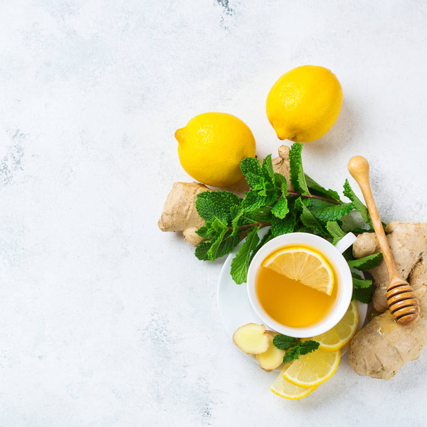 Food and drink, still life health care concept. Ginger tea infusion beverage in white cup with lemon mint honey on a kitchen table for cold and flu winter autumn days. Top view copy space background - Photo, Image