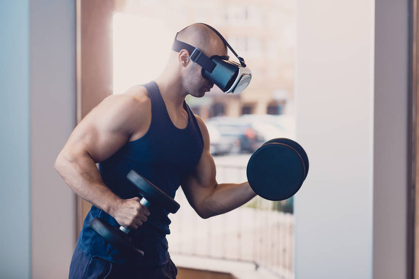 Man wearing virtual reality glasses with dumbbells - Foto, afbeelding