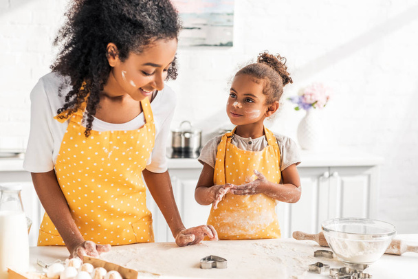 afro-americana mãe e filha fazendo biscoitos com moldes juntos na cozinha
 - Foto, Imagem