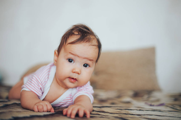 bebé, bebé recién nacido lindo de ojos azules, pelo oscuro, bebé 2 meses en un cuerpo azul acostado sobre su estómago
 - Foto, Imagen