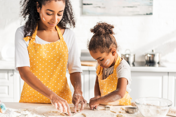 african american mother and adorable daughter preparing cookies with molds in kitchen - Photo, Image