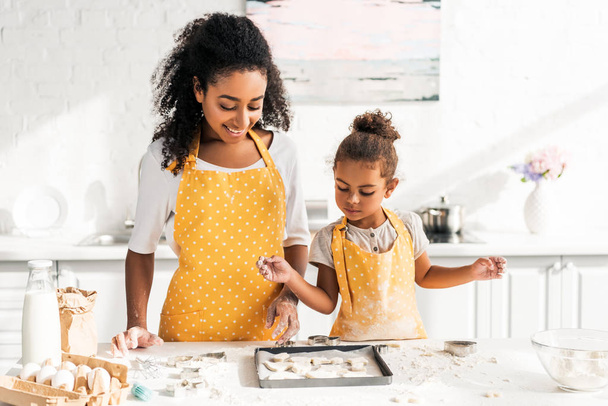afro-amerikai anya és lánya nézi a cookie-kat a konyhában tálca - Fotó, kép