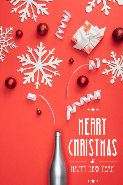 vue du dessus du cadeau, bouteille de champagne, jouets de Noël rouges, rubans blancs et flocons de neige décoratifs disposés isolés sur rouge avec lettrage "joyeux Noël et bonne année"
 - Photo, image