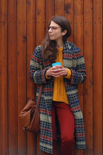 Veselá usmívající se dívka drží kávu jít venku na pozadí. Mladá žena těší čas a usmívá se.  - Fotografie, Obrázek