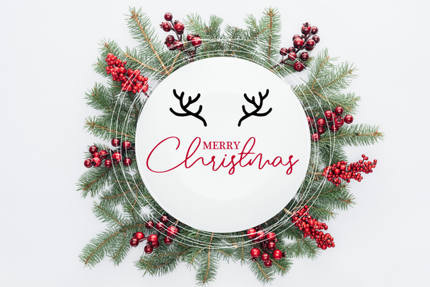 fenyő fa koszorú, karácsonyi díszek, a "boldog karácsonyt" betűkkel elszigetelt fehér középső felső nézetében - Fotó, kép