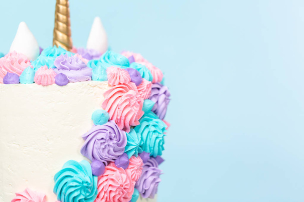 Gourmet unicorn cake with pink and purple buttercream frosting on blue background. - Photo, Image