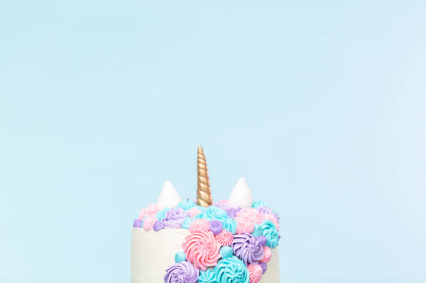 Gourmet-Einhornkuchen mit rosa und lila Buttercreme Zuckerguss auf blauem Hintergrund. - Foto, Bild