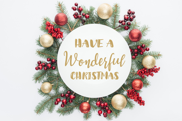 top view of pine tree wreath with Christmas decorations with "have a wonderful christmas" lettering in middle isolated on white - Photo, Image