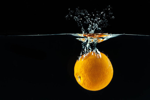 Orange falling into water and making splashes - Фото, зображення