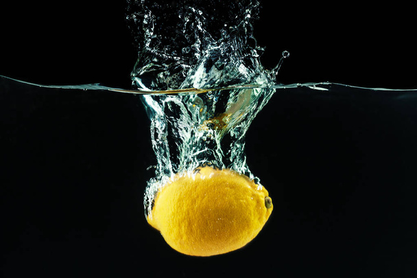 fresh yellow lemon falling into water and making splashes - Photo, Image