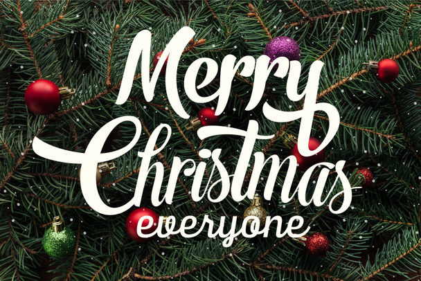 full frame of colorful christmas toys on green pine tree branches with "merry christmas everyone" lettering  - Fotó, kép